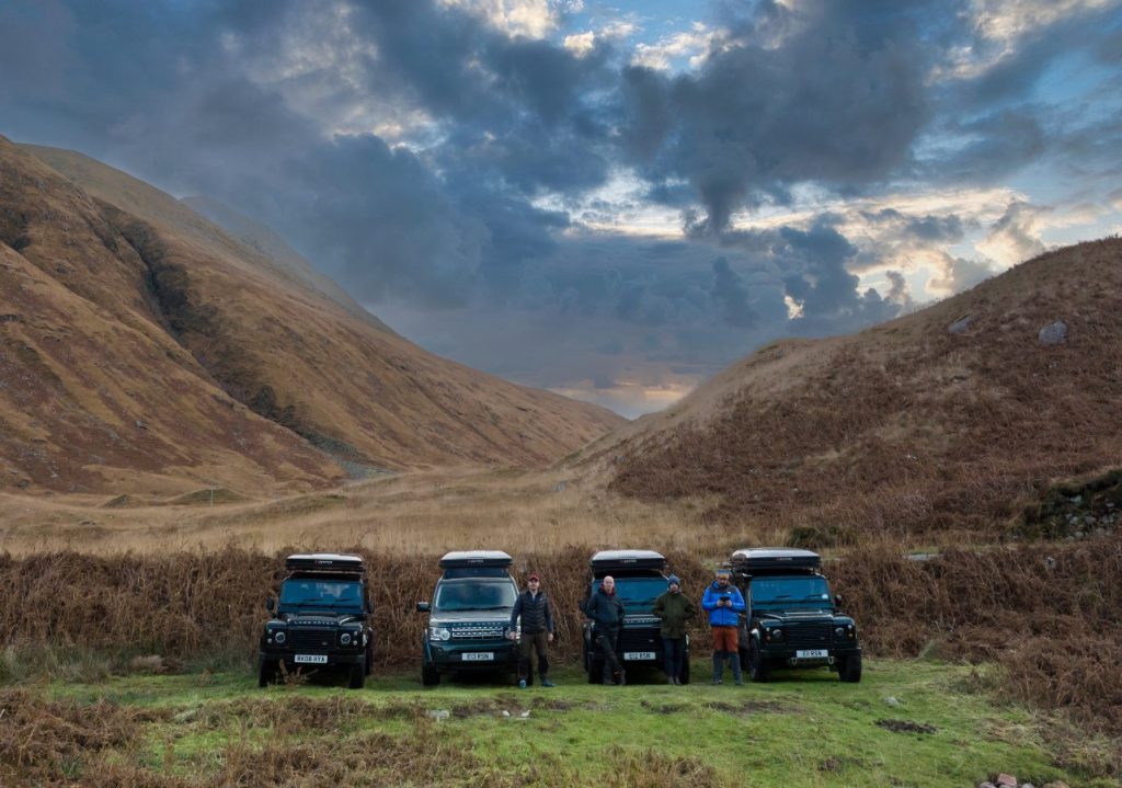 4 Land Rovers with roof tents sit in the Autumn glens of the Scottish Highlands on a group outdoor adventure holiday.