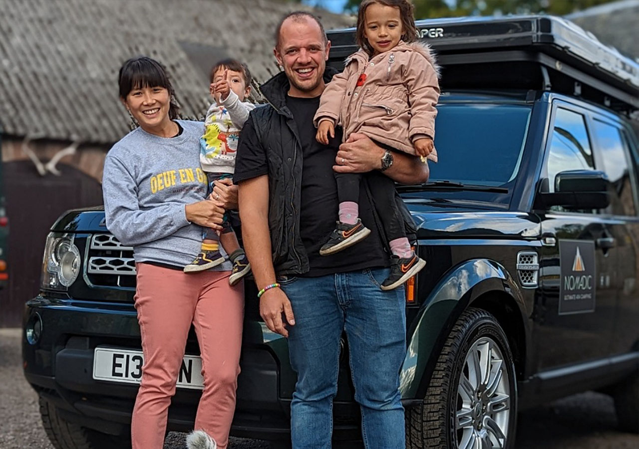 A family standing in front of a Nomadic Scotland Land Rover