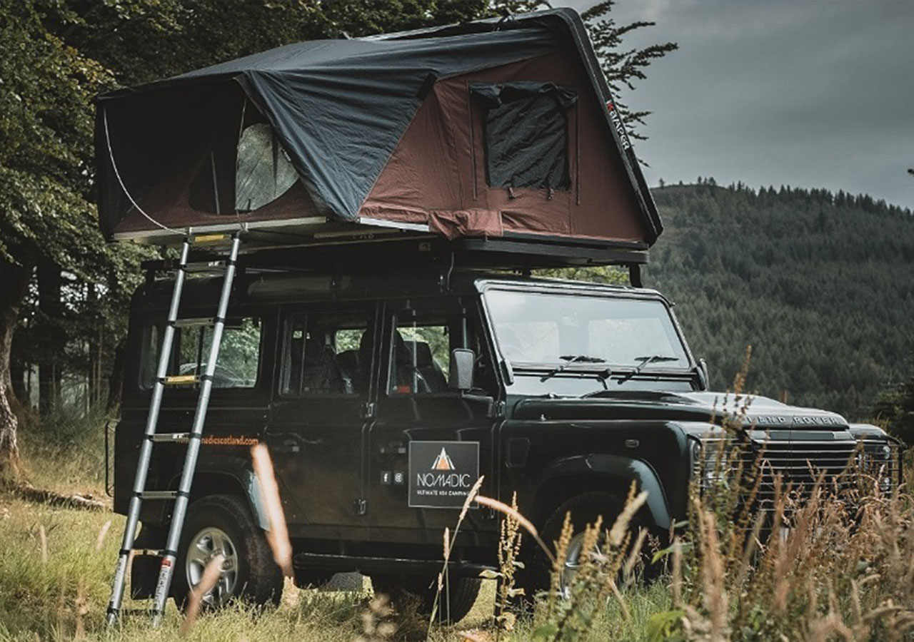 A Nomadic Scotland Land Rover with a roof tent on top