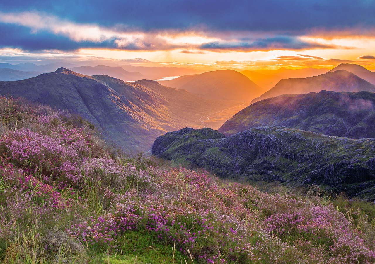 Glencoe at sunset with rolling heather covered hills in the foreground