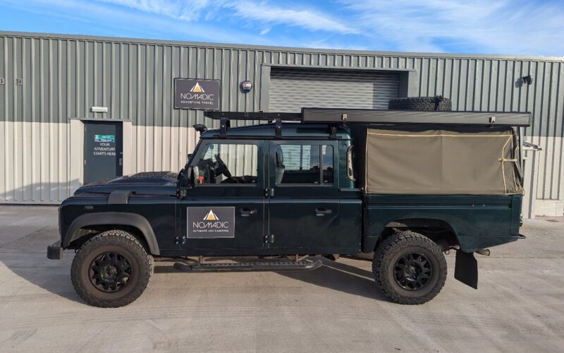 A Land Rover Defender 130 4x4 vehicle for hire on a sunny day in Scotland.