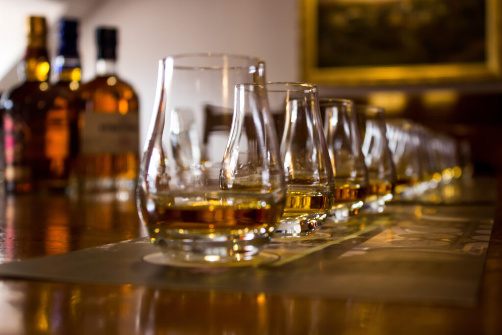 A line of tasting glasses filled with different types of Whiskies for tasting, a common feature of whisky tours in Scotland